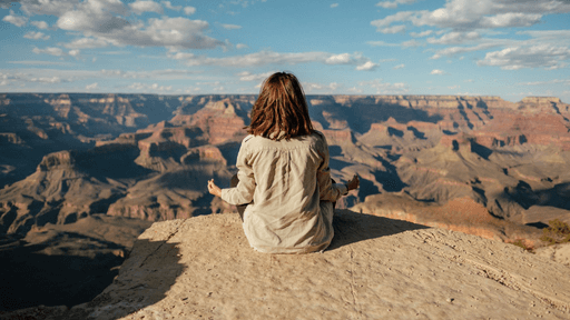 Une personne assise en tailleur admirant la vue du Grand Canyon