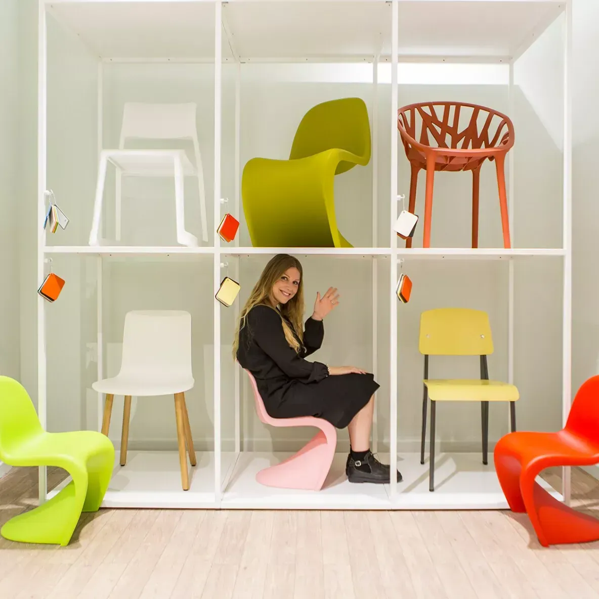 Dipendente seduta su una sedia di design in una libreria espositiva con altre sedute colorate