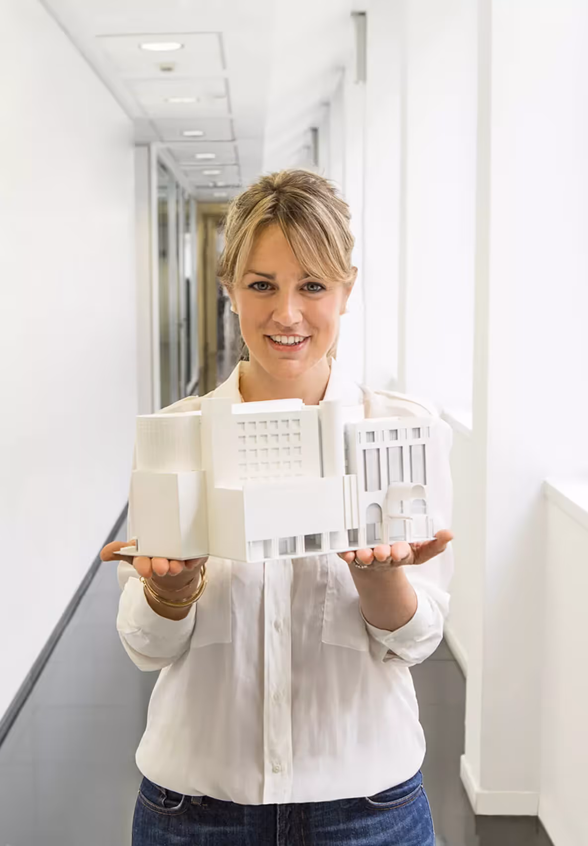 Una dipendente mostra il modellino di un edificio in un corridoio dell’ufficio